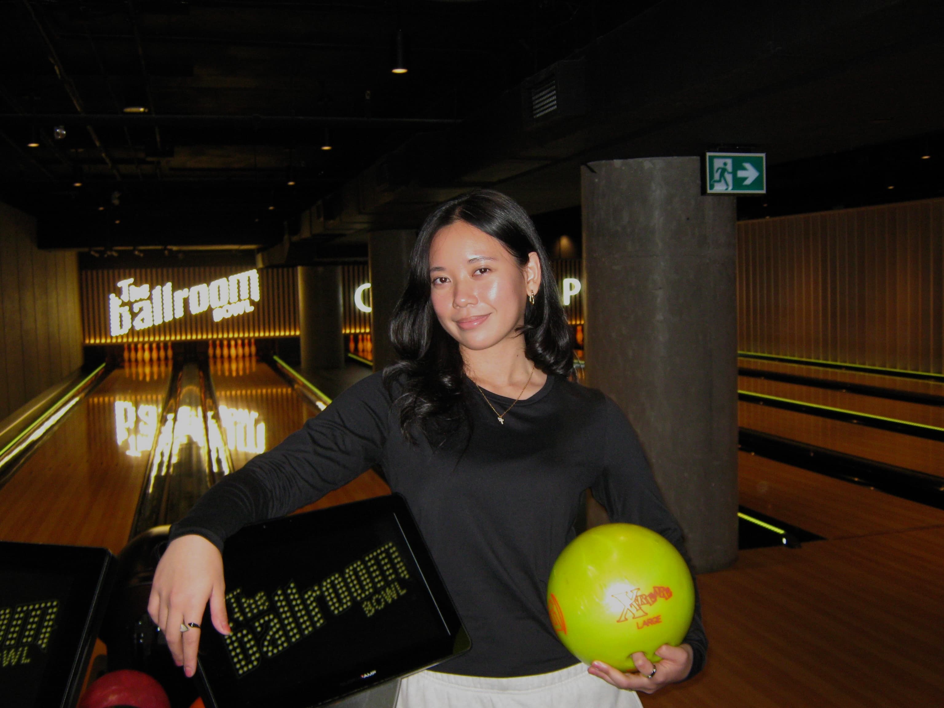 Natasha at a bowling alley holding a yellow bowling ball